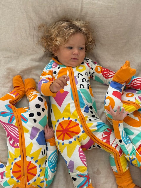 3 x babies in multi coloured long sleeve baby onesie with fold over hand and foot cuffs in unisex design. each print is unique