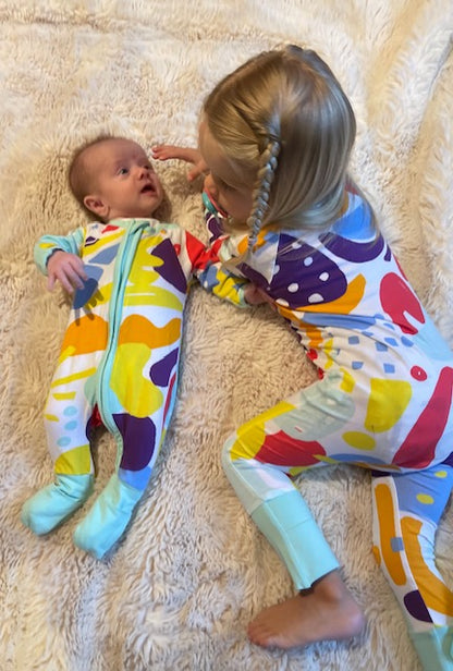 Baby & toddler wearing multi coloured long sleeve baby onesie with fold over hand and foot cuffs in unisex design