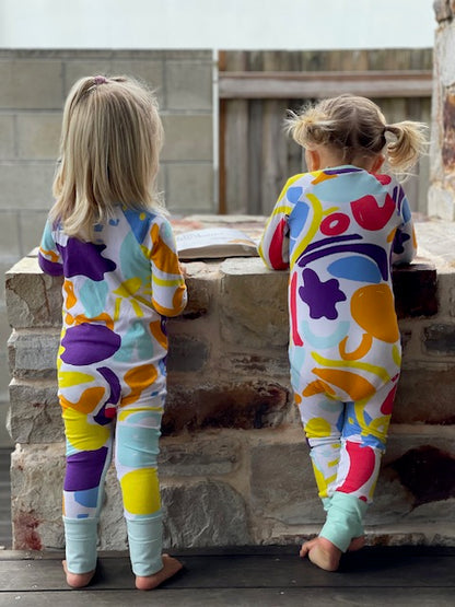 two toddlers wearing multi coloured long sleeve baby onesie with fold over hand and foot cuffs with unisex design