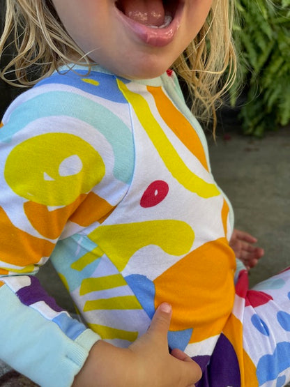 Close up of toddler wearing multi coloured long sleeve baby onesie 