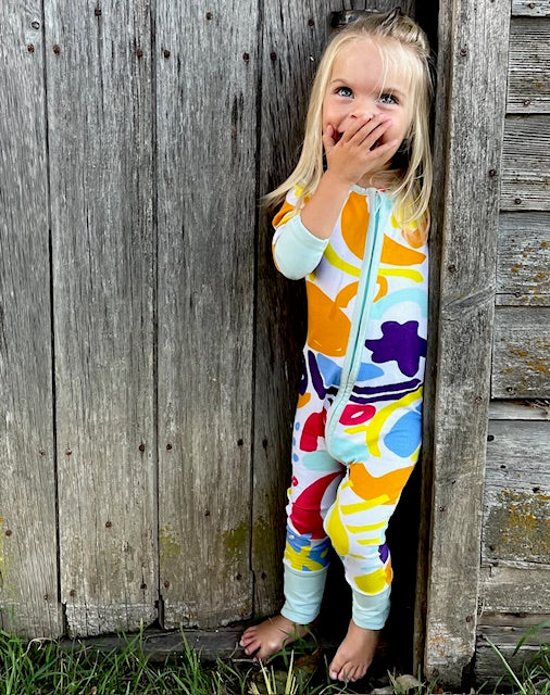 Toddler wearing multi coloured long sleeve baby onesie with fold over hand and foot cuffs 