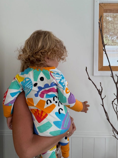 showing back of multi coloured long sleeve baby onesie with fold over hand and foot cuffs in unisex design