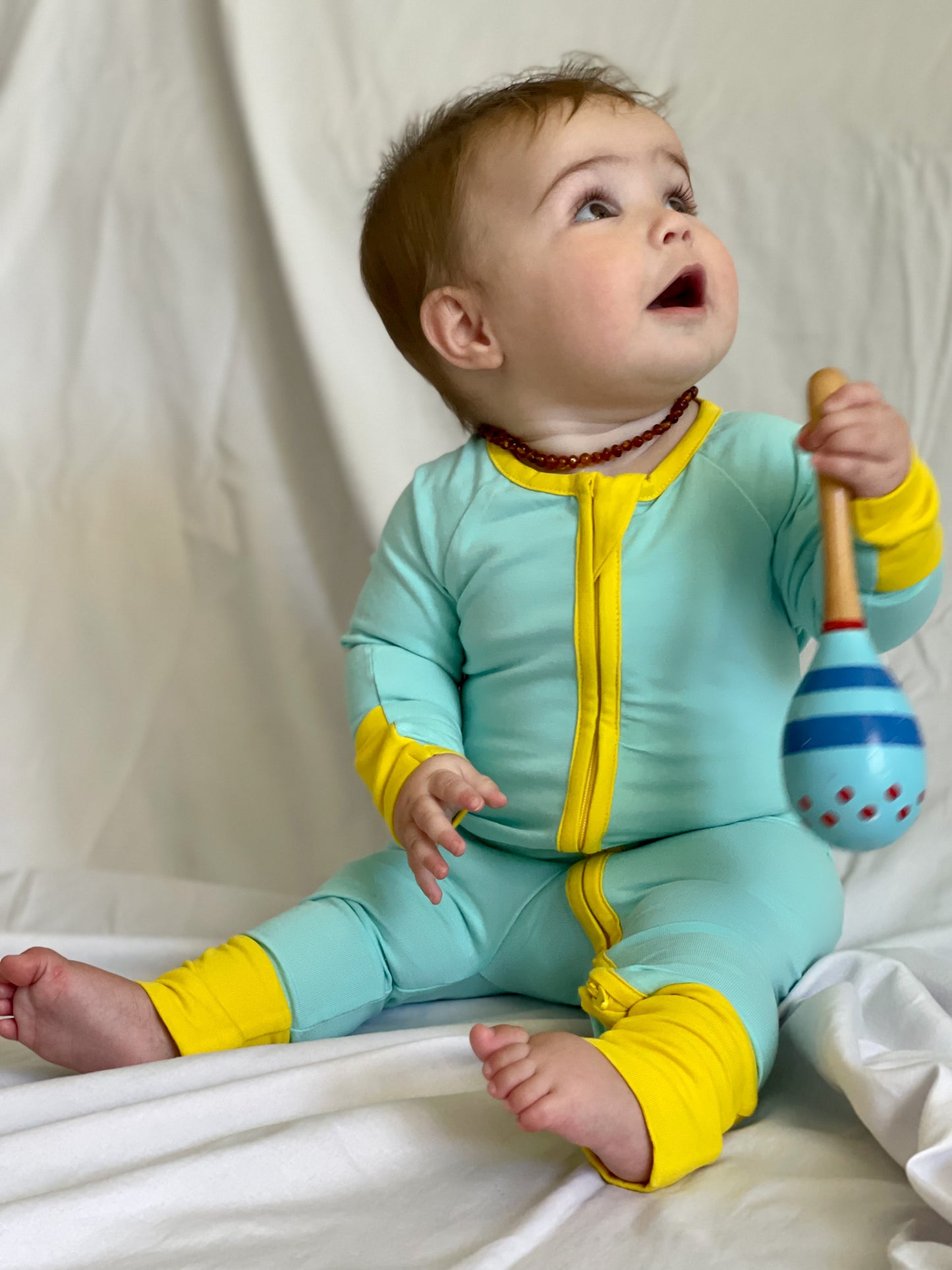 solid teal long sleeve baby onesie with dandelion trim with fold over hand & foot cuffs and double zip